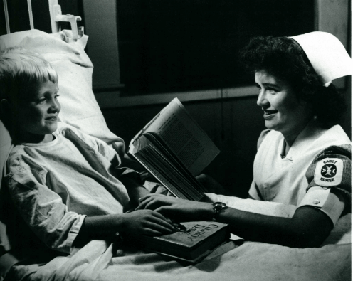 Historic nurse reading to child patient